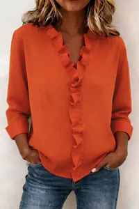 Detail shot of orange cotton linen top with feminine ruffle edges and V-neckline
