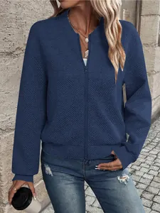 Dettaglio della giacca blu navy con zip, motivo a spina di pesce strutturato e polsini a coste.