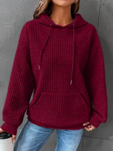 Close-up of wine red waffle knit hoodie featuring front pocket and drawstring hood