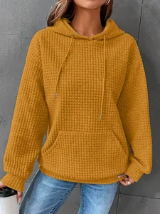 Detailed view of women's mustard yellow waffle knit hoodie featuring kangaroo pocket.