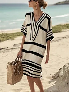 Robe d'été élégante à rayures noires et blanches avec col en V sur une plage tropicale