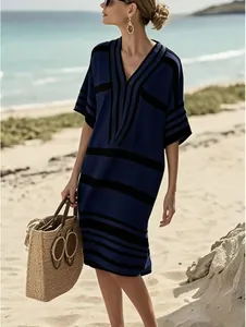 Robe élégante à rayures bleues et noires à col en V présentée dans un décor de plage.