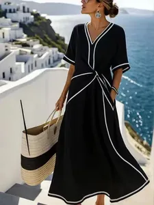 Detail view of a black V-neck maxi dress with elegant white piping and waist knot