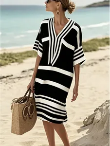 Femme élégante portant une robe à rayures noires et blanches sur une plage ensoleillée