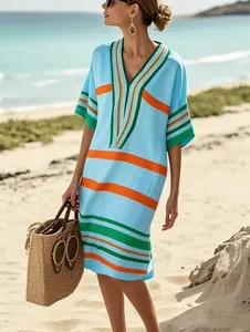 Vue lifestyle d'une robe midi rayée bleue claire sur une plage de vacances ensoleillée