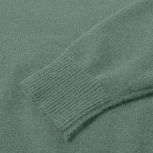 Close-up detail of soft sage green knit sweater showing ribbed cuff texture and quality