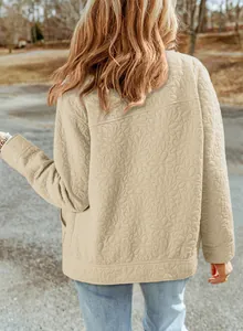 Dettaglio del motivo floreale trapuntato sul retro di una giacca beige ampia con bottoni