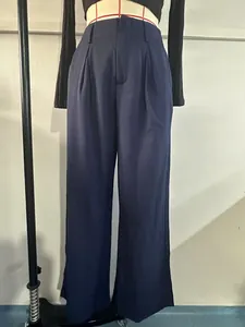 Close-up of pleated high waistband and fabric texture on navy blue straight-leg pants