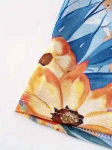 Nahaufnahme von böhmischem Blumenrockstoff mit feinen Nähten und lebhaftem orangefarbenem Druck.