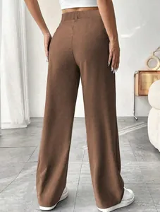 Back view of brown high-waisted straight-leg trousers in a minimalist interior setting