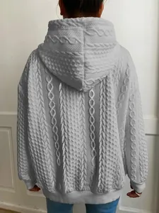 Detalle en primer plano de textura jacquard de punto trenzado en sudadera para mujer.