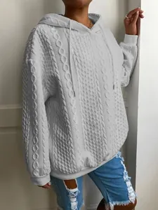 Vista detallada de una sudadera con capucha de punto de ochos blanca sobre una modelo