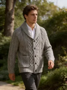Detailansicht eines grauen Herren-Cardigans mit Schalkragen und Zopfmuster in einem Garten