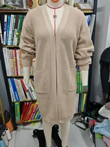 Detailansicht eines langen beigen Strick-Cardigans mit zwei Vordertaschen an einer Puppe