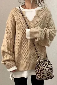 Dettaglio di maglione beige a trecce con vestibilità oversize e scollo a strati