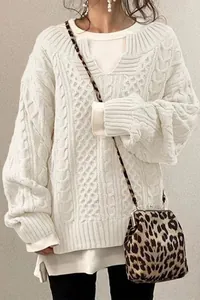 Dettaglio di un maglione a trecce color crema da donna con borsa leopardata alla moda