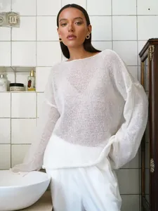 Pull élégant en maille transparente blanche pour femme dans une salle de bain épurée
