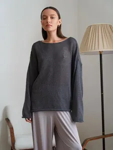 Vue détaillée d'un pull en maille ajourée gris ample pour femme dans un salon.