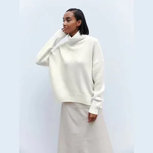 Model wearing a soft ivory white high turtleneck sweater with ribbed knit details