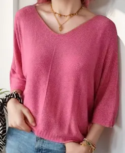 Detailed macro view of pink V-neck knit sweater featuring loose three-quarter sleeves