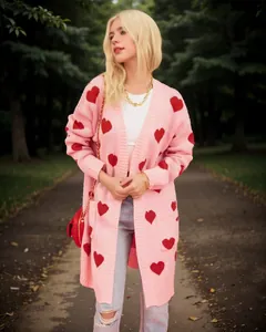 Stylish pink long knit cardigan with red heart patterns worn by a fashion model in a park.