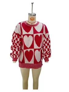 Primo piano di un maglione oversize rosso e bianco con motivi a cuore e scacchi
