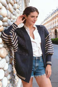 Dettaglio cardigan in maglia blu con motivo a stelle traforate e maniche a righe.