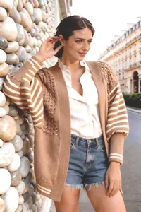 Modella che indossa un cardigan marrone a maglia traforata con maniche a righe all'aperto.
