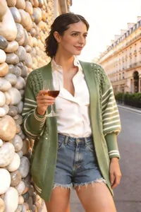 Dettaglio ravvicinato del cardigan in maglia verde con strisce bianche a contrasto