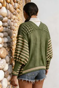 Dettaglio posteriore di un cardigan in maglia a righe verde e beige con lavorazione a traforo