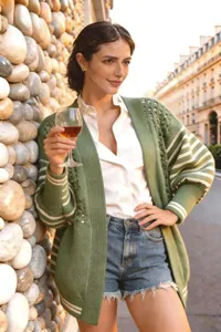 Donna all'aperto con indosso un cardigan in maglia traforata verde con maniche a righe