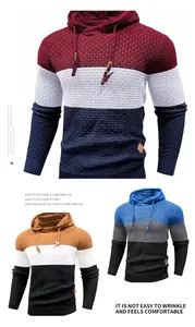 Close-up of men's textured color-block hoodie sweaters in burgundy, blue, and camel