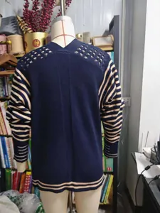 Dettaglio del cardigan in maglia blu scuro con maniche a righe e spalle traforate