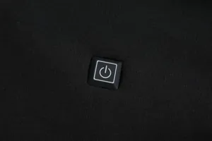 Close-up detail of the smart power button control on a black USB heated hoodie sweatshirt