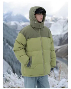 Detailed outdoor shot of a two-tone olive green hooded puffer jacket in snowy mountains