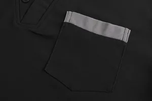 Macro close-up of a black pique polo shirt pocket featuring grey contrast trim details