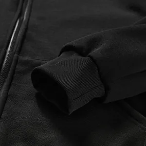 Vue détaillée du poignet côtelé et de la texture du tissu d'un sweat à capuche noir zippé