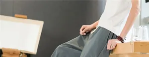 Gros plan d'un pantalon d'homme en lin bleu grisâtre à coupe ample dans un décor épuré.