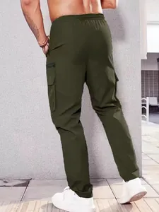 Back view of men's olive green multi-pocket cargo pants in an urban outdoor setting.