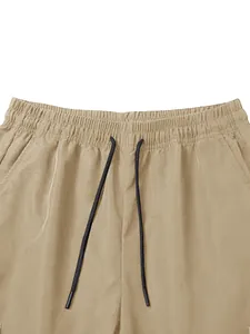 Close-up of elastic waistband with black drawstrings on khaki cargo pants.