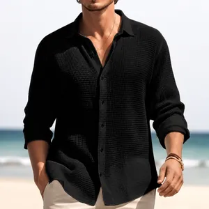 Detail view of men's black textured long-sleeved casual button-down shirt at beach.