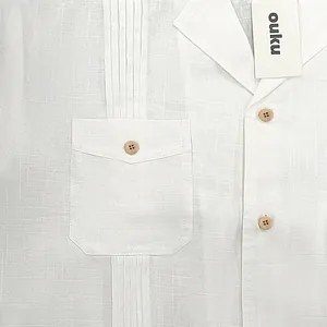 Dettaglio camicia bianca in cotone e lino con trama, pieghe e bottoni in legno