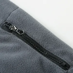 Close-up of a durable black plastic zipper on soft grey fleece sweatshirt fabric