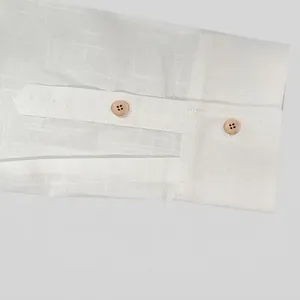 Dettaglio del polsino di una camicia bianca in cotone e lino con bottoni in legno