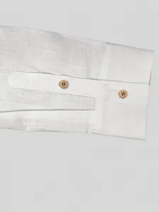 Dettaglio ravvicinato del polsino di una camicia bianca da uomo in cotone e lino
