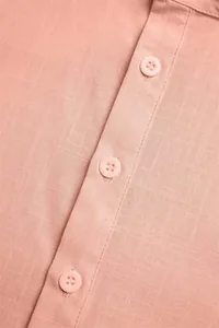 Detail macro view of a pink summer cotton linen shirt featuring a stand collar and tonal buttons.