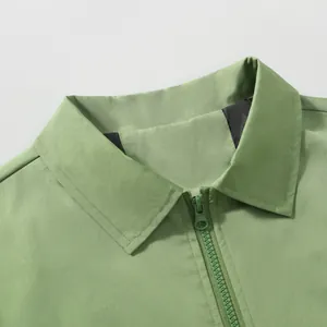 Detail showing the classic collar and smooth resin zipper of a sage green windproof jacket