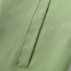Close-up detail of high-quality stitching and pocket on green windproof jacket