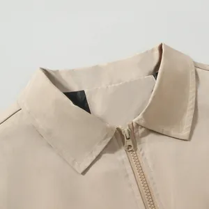 Close-up of a khaki windproof jacket's collar and durable resin zipper detail.