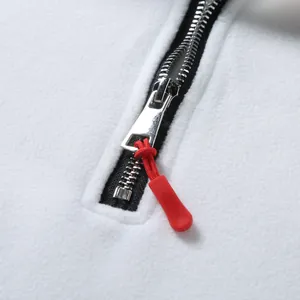 Close-up detail of white polar fleece sweatshirt featuring a silver zipper and red cord pull